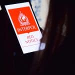 Mulher observando aplicativo da lista vermelha da Interpol