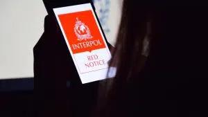 Mulher observando aplicativo da lista vermelha da Interpol