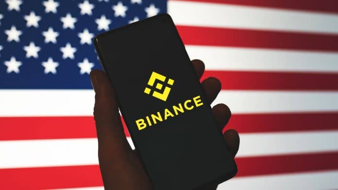Celular com aplicativo da Binance e bandeira dos EUA.