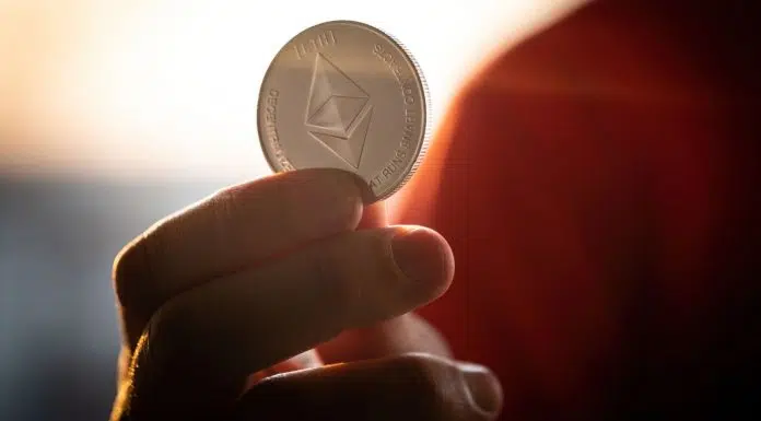 Investidor segurando moeda física de Ethereum.