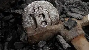 Picareta de mineração enferrujada e moeda de Bitcoin.