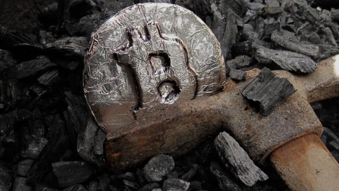 Picareta de mineração enferrujada e moeda de Bitcoin.