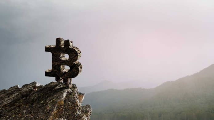 Símbolo do Bitcoin em topo de montanha.