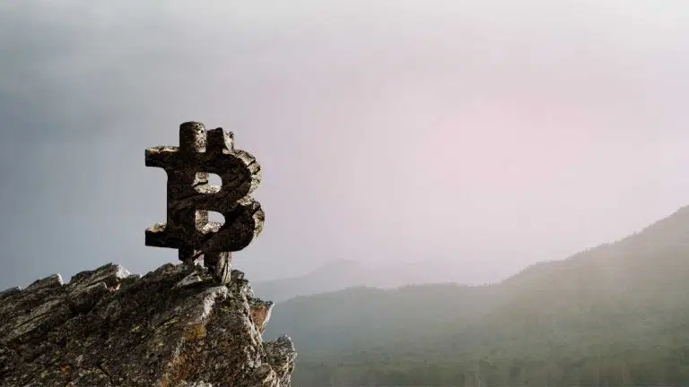 Símbolo do Bitcoin em topo de montanha.