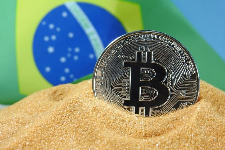 Bitcoin em monte de areia com bandeira do Brasil ao fundo Ewan Kennedy