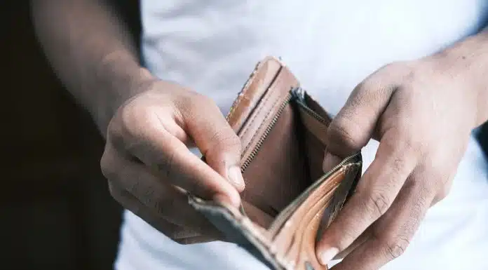 Homem abrindo carteira vazia após perder dinheiro