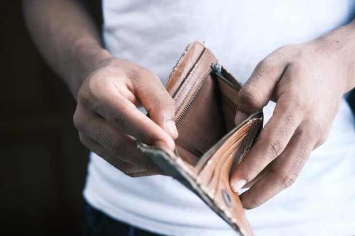 Homem abrindo carteira vazia após perder dinheiro