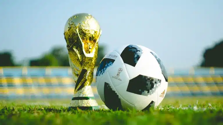 Taça da Copa do Mundo em campo de futebol ao lado de bola
