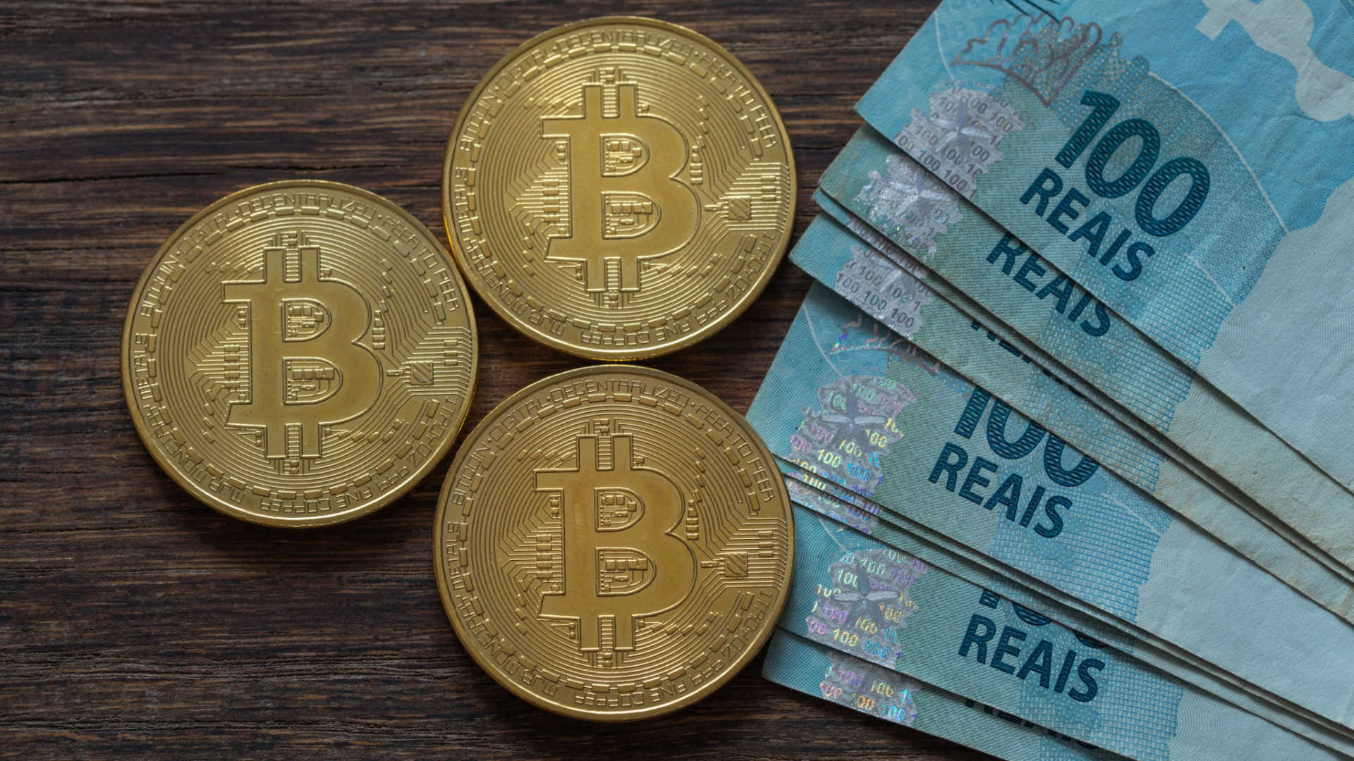 Moedas de Bitcoin e notas de Real.