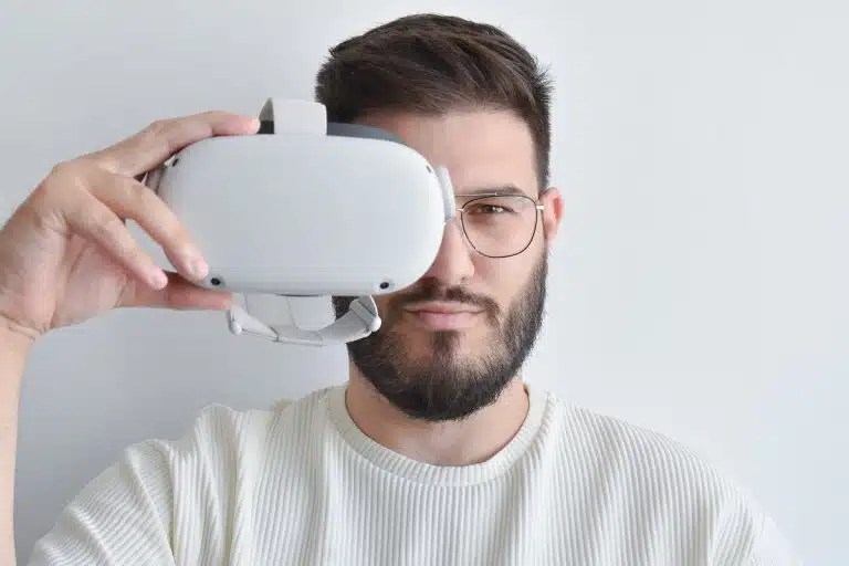 Homem segurando óculos de realidade virtual, utilizado em metaversos