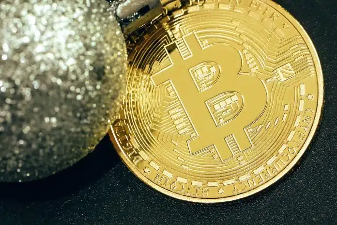 Moeda bitcoin próxima de uma bola prateada de natal