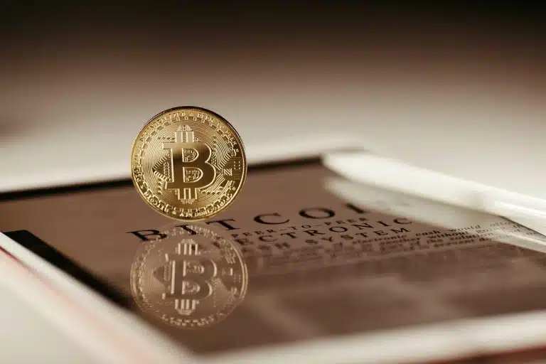 Moeda simbólica do bitcoin sobre tablet com paper escrito por Satoshi Nakamoto