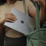 Mulher guardando notebook com símbolo da Microsoft em mochila e criptomoedas