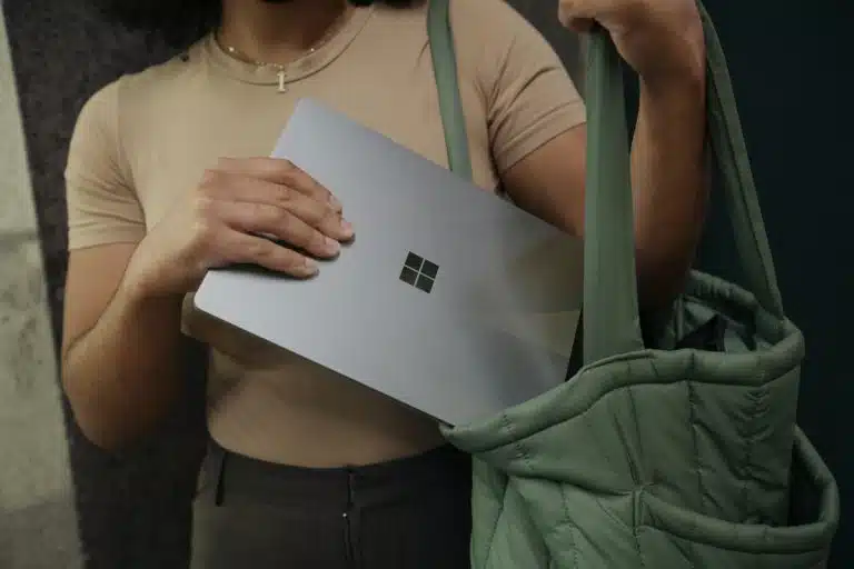 Mulher guardando notebook com símbolo da Microsoft em mochila e criptomoedas