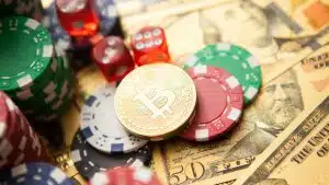 Moeda de Bitcoin entre dados, fichas e outros itens de um cassino.