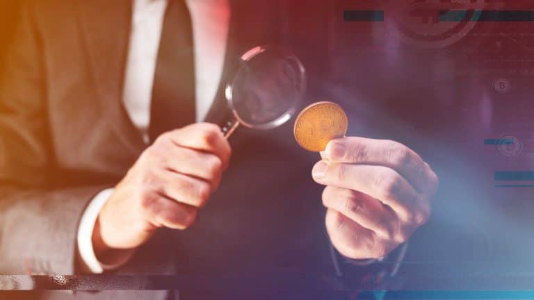 Investigador analisando moeda de bitcoin.