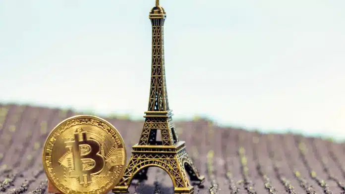 Moeda de Bitcoin ao lado de torre Eiffel.