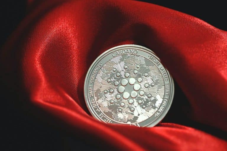Criptomoeda Cardano simbólica sobre pano vermelho