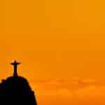 Cristo Redentor em destaque com céu laranja