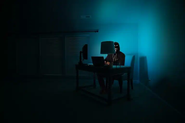 Homem no canto com máscara utilizando computador