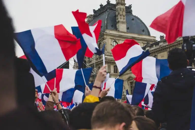 Pessoas agitando a bandeira da França em frente ao Louvre