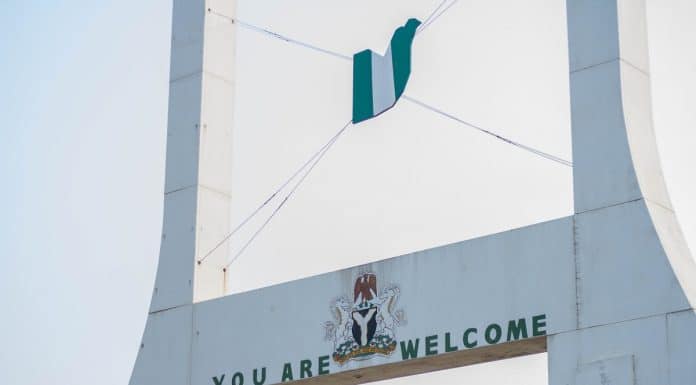 Placa com dizeres de bem-vindo próxima de bandeira da Nigéria