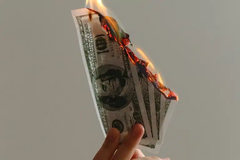 Mão segurando Dólar pegando fogo