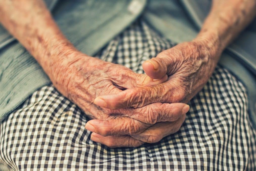 Mãos cruzadas de idosa