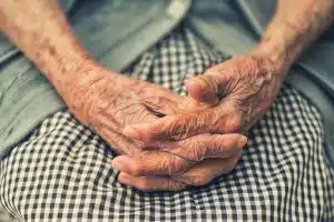 Mãos cruzadas de idosa