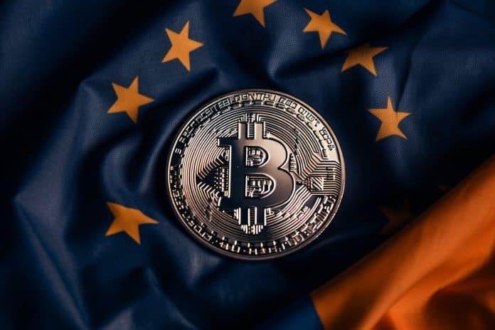 Bandeira da União Europeia e moeda de Bitcoin.
