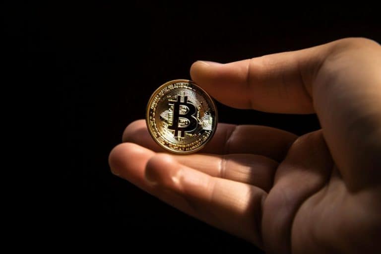 Mão segurando moeda de Bitcoin. Midjourney.
