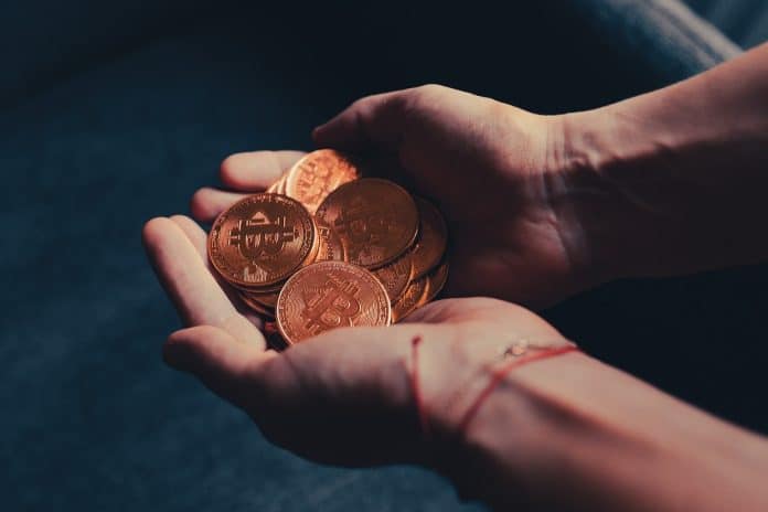 Mãos segurando muitos bitcoins