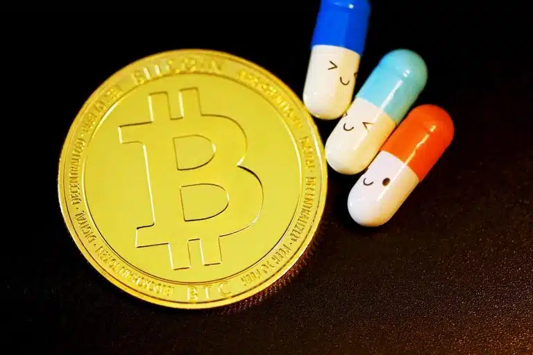 Símbolo do bitcoin próximo de pílula laranja com rosto feliz
