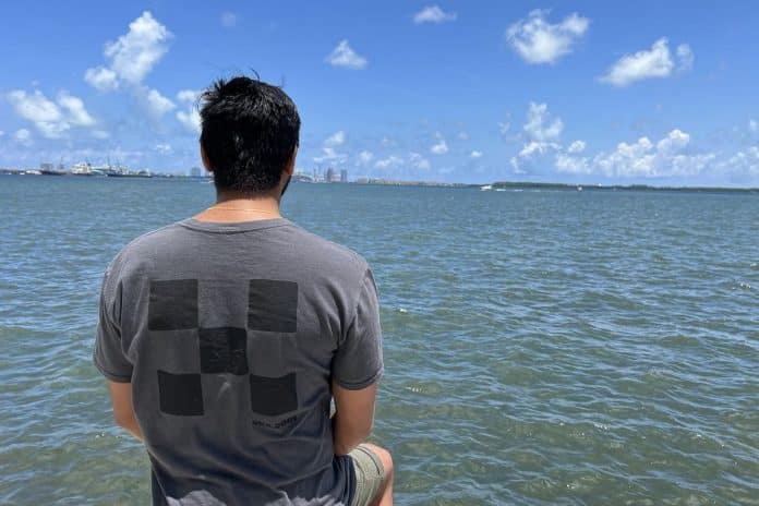 Homem com camisa com símbolo da corretora de criptomoedas OKX