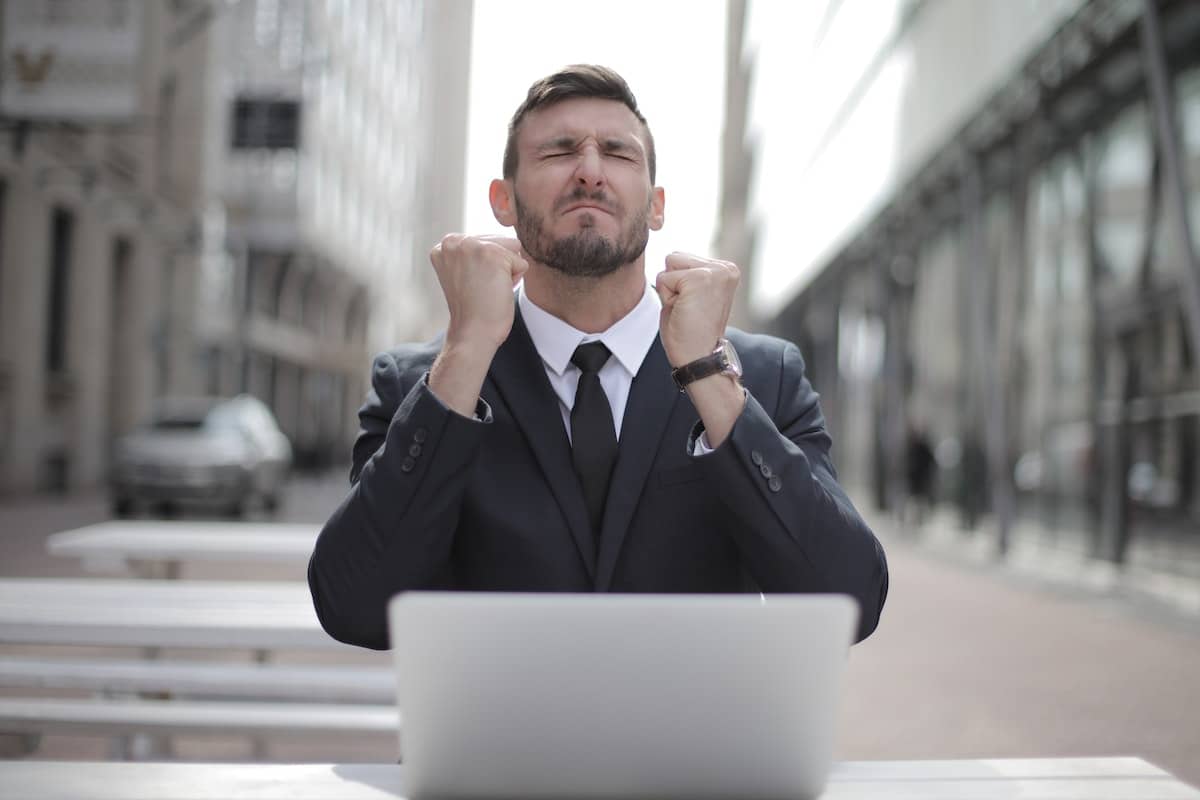 Homem em frente ao computador comemorando