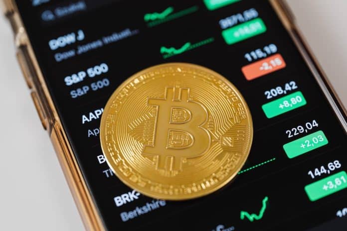 Bitcoin com aplicativo de preços ao fundo
