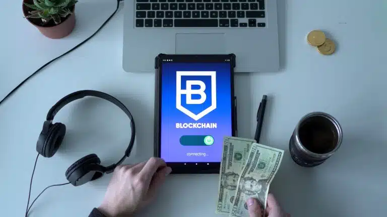 Consumidor segurando notas de Dólar enquanto acessa aplicativo com acesso a blockchain