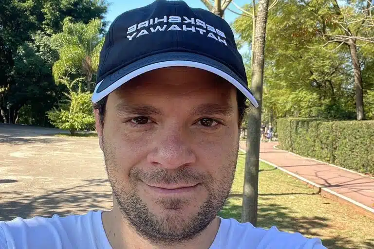 Influencer de finanças Tiago Reis com boné de empresa do Warren Buffet hater crítico do bitcoin