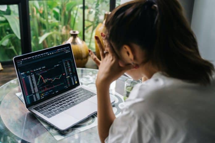 Mulher olhando para tela de negociação de criptomoedas de corretora