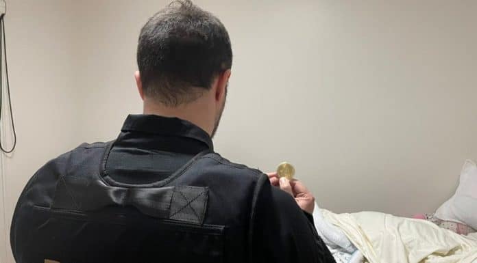 Agente da PF segurando bitcoin simbólico