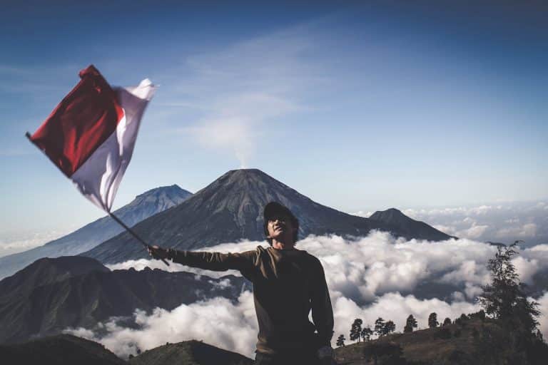 Homem agitando bandeira da Indonésia em topo de montanha