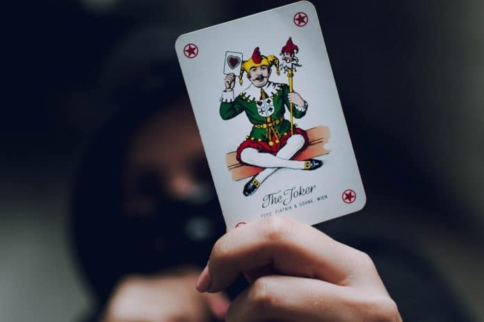 Homem mascarado com a carta de um coringa na mão
