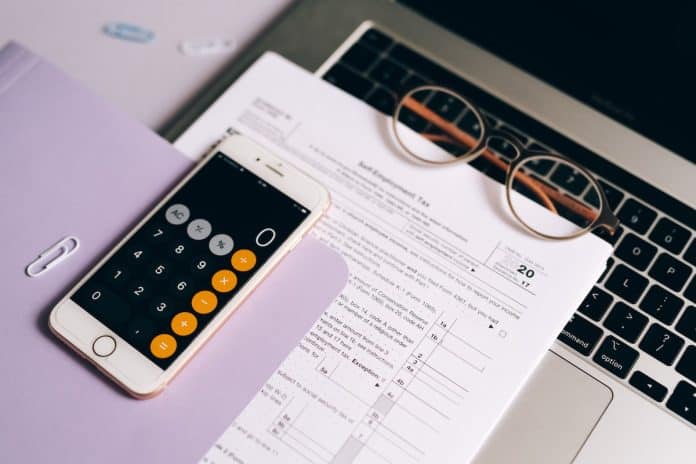 Calculadora em celular próxima de guia de imposto sobre notebook