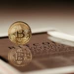 Moeda simbólica do bitcoin sobre tablet com whitepaper em destaque