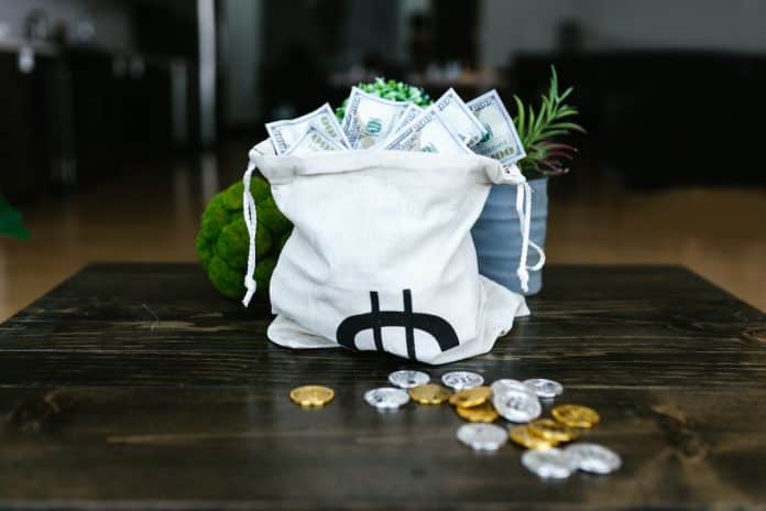 Saco de dinheiro próximo de criptomoedas em mesa