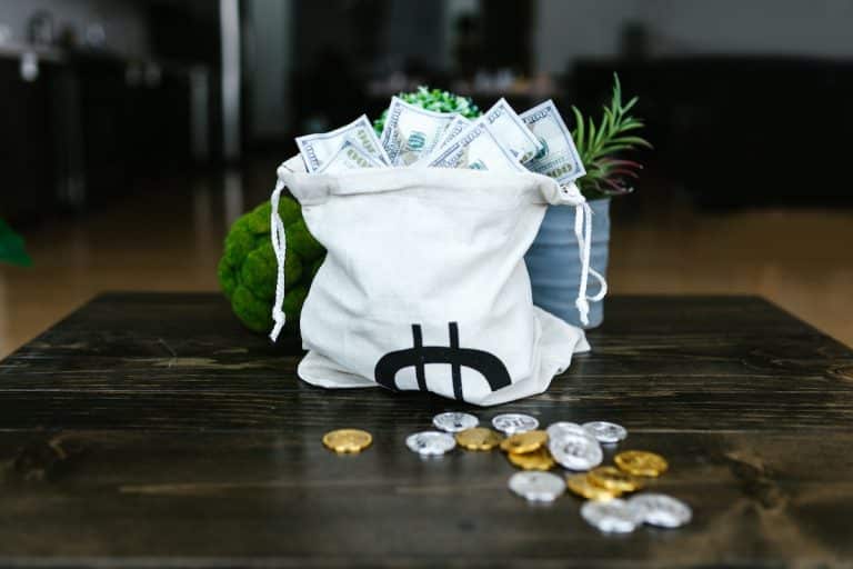 Saco de dinheiro próximo de criptomoedas em mesa