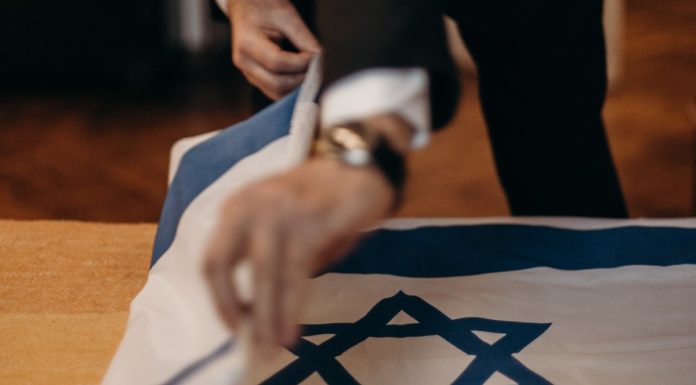 Homem dobrando bandeira de Israel