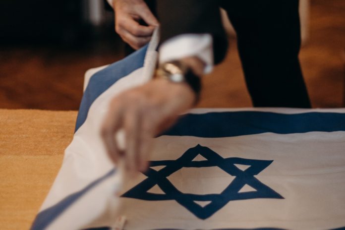 Homem dobrando bandeira de Israel