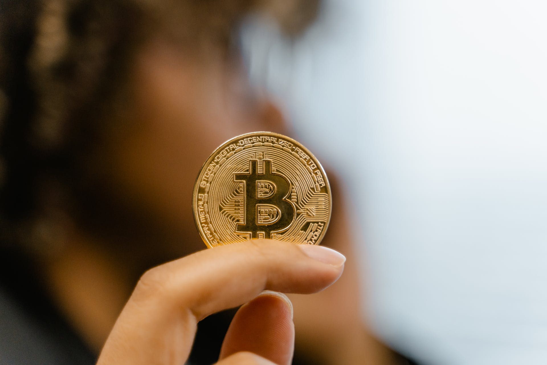 Investidor segurando moeda de Bitcoin. Foto de Tima Miroshnichenko/Pexels.