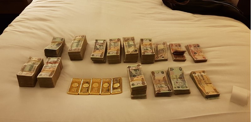 Maços de dinheiro e lingotes de ouro confiscados do grupo pela polícia. Reprodução.